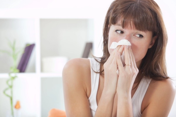 woman sneezing due to poor indoor air quality at home