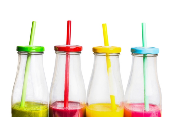 different colored juices and straw in a clear bottle