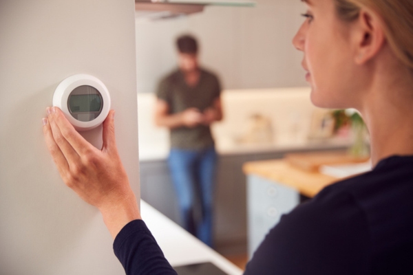woman adjusting wall mounted AC thermostat depicting misuse