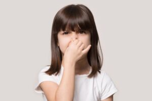 kid pinching nose depicting bad smell coming from AC