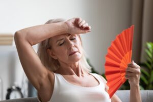 lady feeling warm while using red hand fan due to broken AC