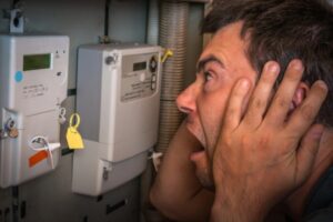 man looking shocked while checking electricity meter