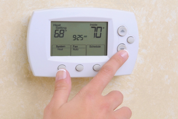 woman's hand adjusting thermostat