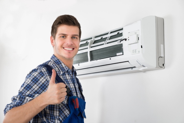 HVAC technician doing a thumbs up after installing ductless HVAC system for a client