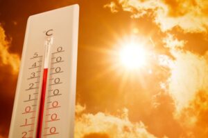 weather thermometer and sunny sky depicting extreme summer temperature