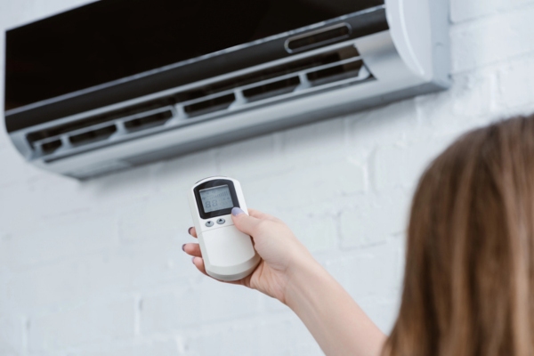 cropped shot of a woman controlling ductless air conditioner with a remote