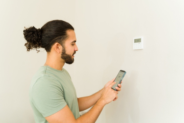 homeowner synching smart phone to home thermostat
