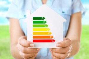 Female hands holding house with energy efficiency scale depicting AFUE vs AFUE2