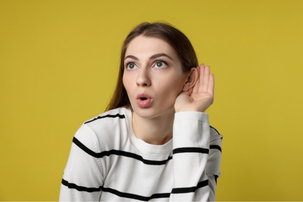 Woman showing hand to ear gesture due to strange heating system sounds
