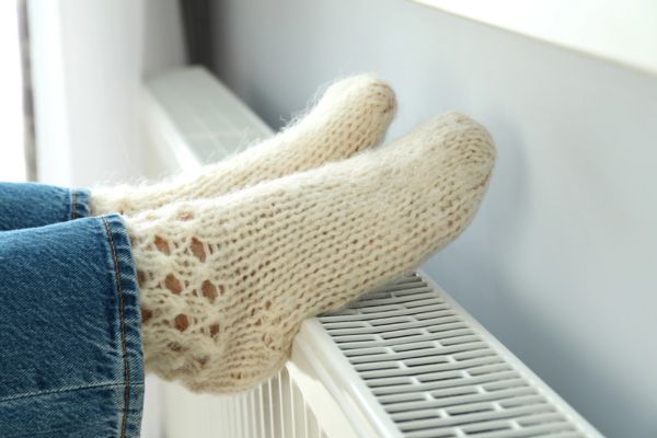 cropped view of a female's feet keeping warm on a heating radiator