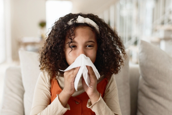 young girl blowing nose on a tissue due to poor indoor air quality