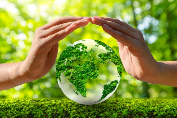 hand protecting Earth in nature background depicting Environmental Responsibility