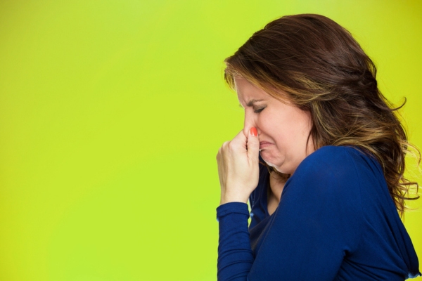 woman covering nose due to odd smell coming from furnace