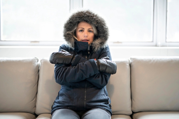 woman wearing winter coat and gloves while on the couch due to furnace failure
