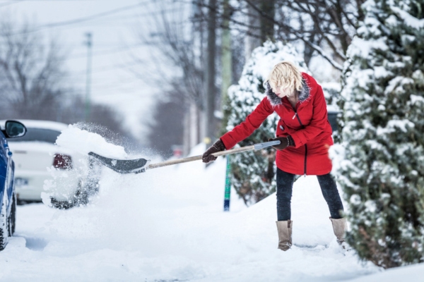 woman shoveling her front yard after a winter storm