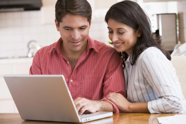 Couple in the kitchen with laptop Checking HVAC Company References
