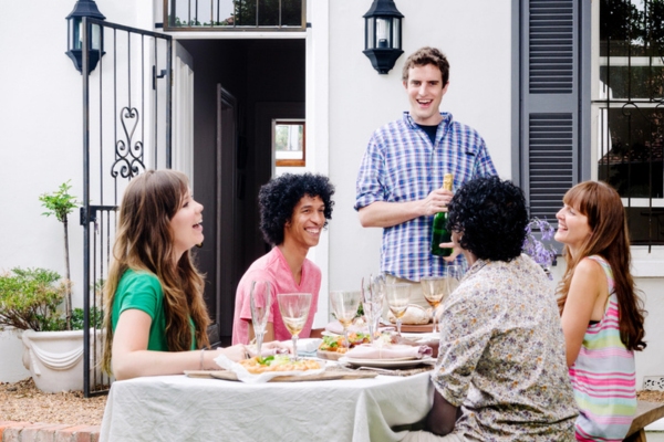 friends smiling while social drinking and eating outdoors
