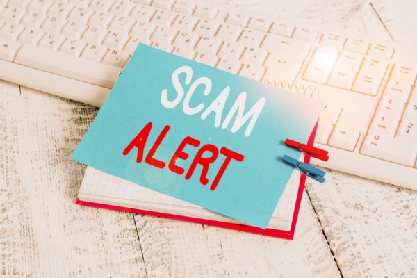 note that says SCAM ALERT on top of a keyboard