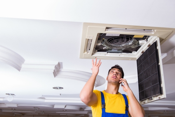 HVAC technician tending to indoor air conditioner unit