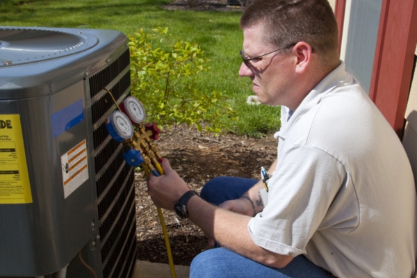 HVAC technician tending to outdoor AC condenser