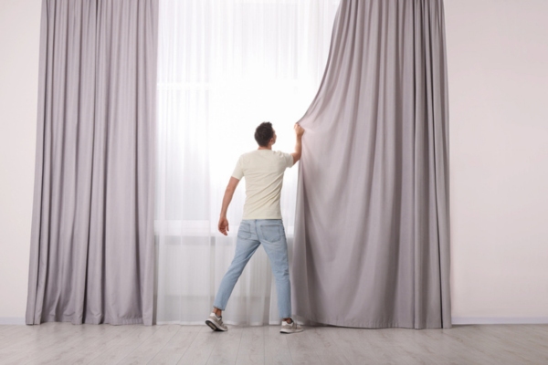 man closing curtains at home to keep home cool