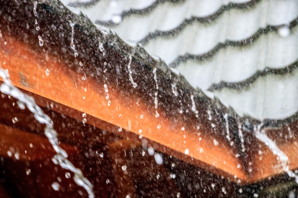 heavy rainfall with water flowing down from a roof