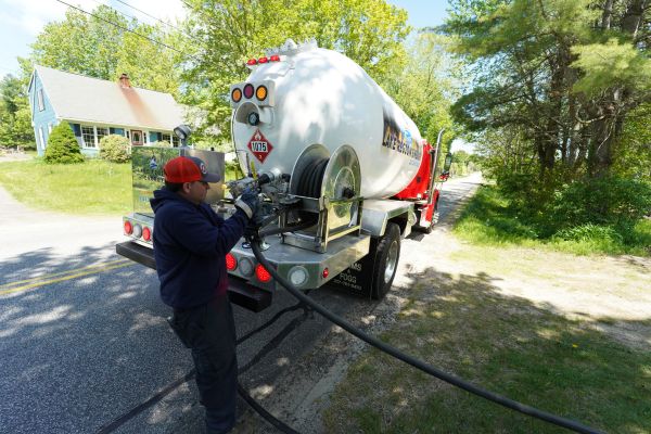 New Gloucester, ME technician delivering propane from a service truck to a residential property