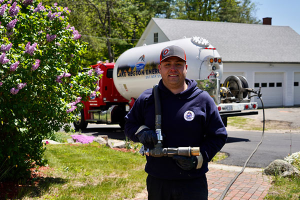 New Gloucester, ME technician holding propane delivery equipment near service truck