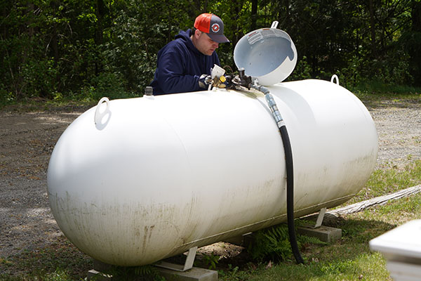 New Gloucester, ME technician refilling a residential propane tank with a hose