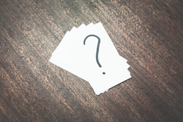 question mark written at the back of a business card depicting FAQs About HVAC Surge Protection